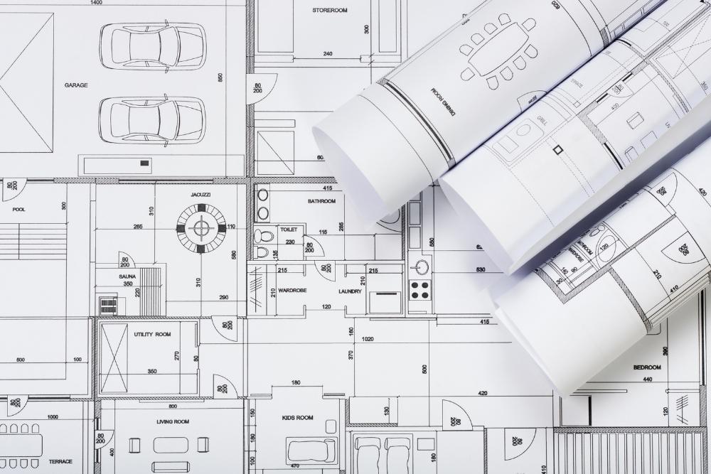 Detailed architectural house plan blueprints laid out flat with several rolled architectural drafts-